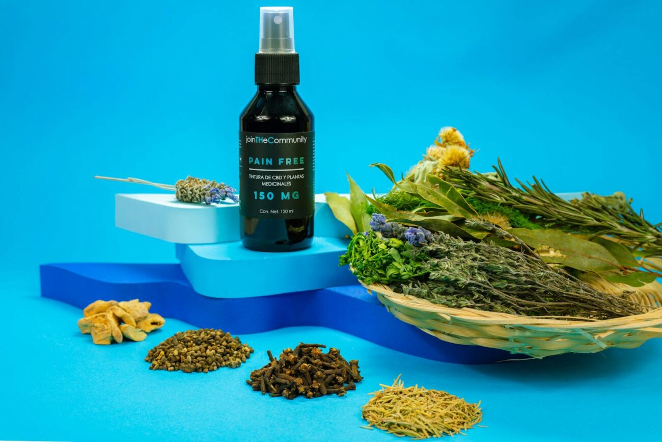 A black spray bottle of herbal pain relief with natural ingredients on a blue background.