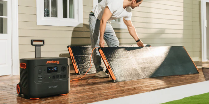 A Jackery portable solar generator power station with solar panel being set up on a deck