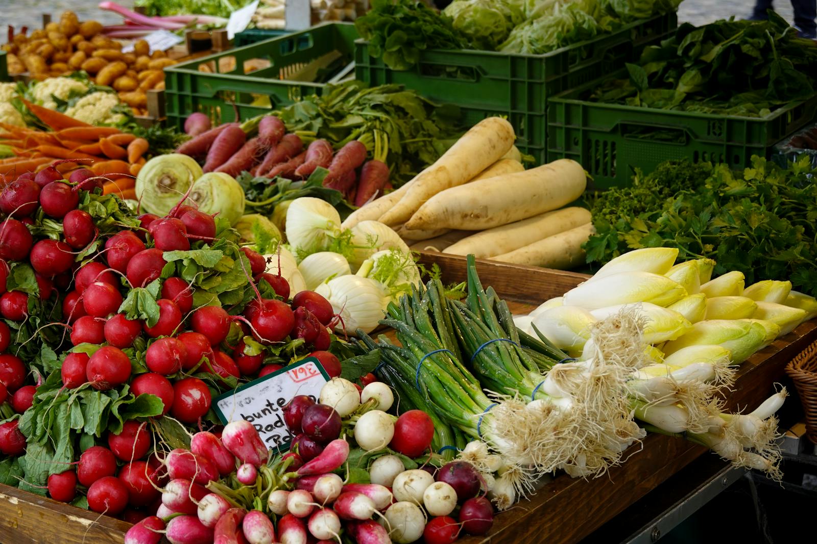 Fresh seasonal vegetables at a farmers market stall showing locally grown produce with diverse secondary metabolite profiles developed under natural field conditions
