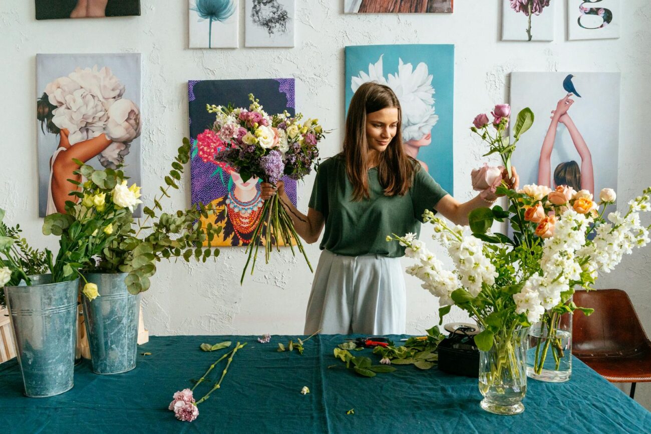 Florist arranging diverse flower species including roses and eucalyptus showing the composition process of combining complementary volatile compound profiles and structural forms in floral designFlorist arranging diverse flower species including roses and eucalyptus showing the composition process of combining complementary volatile compound profiles and structural forms in floral design