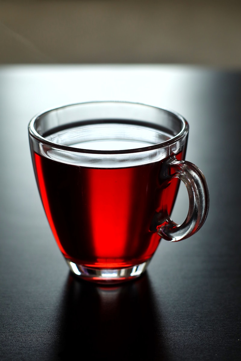 Deep red hibiscus tea in cup showing delphinidin and cyanidin anthocyanin pigments extracted from Hibiscus sabdariffa dried calyces through hot water infusion with characteristic pH dependent colour from acidic organic acid content.