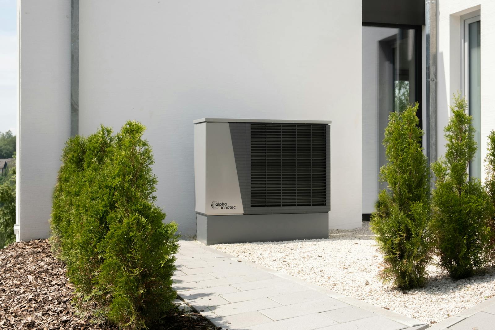 An air source heat pump unit installed outside a residential home extracting heat from outdoor air for home heating