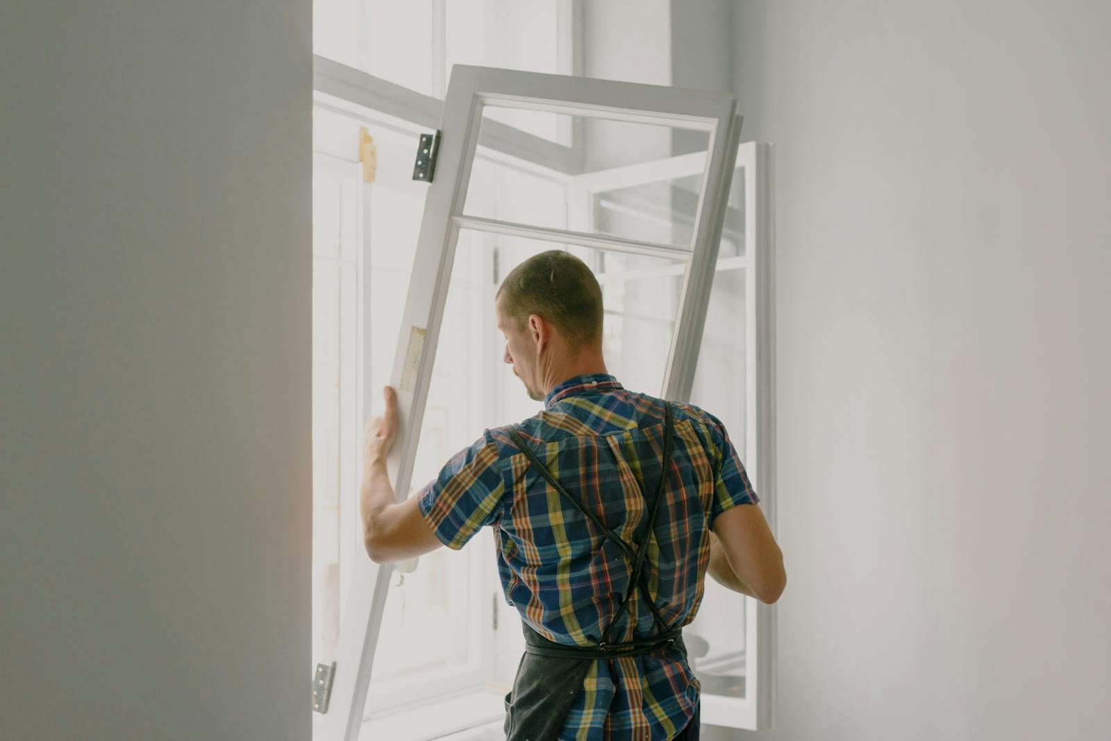 A worker installing a new window frame as part of a home energy efficiency improvement to reduce heat loss