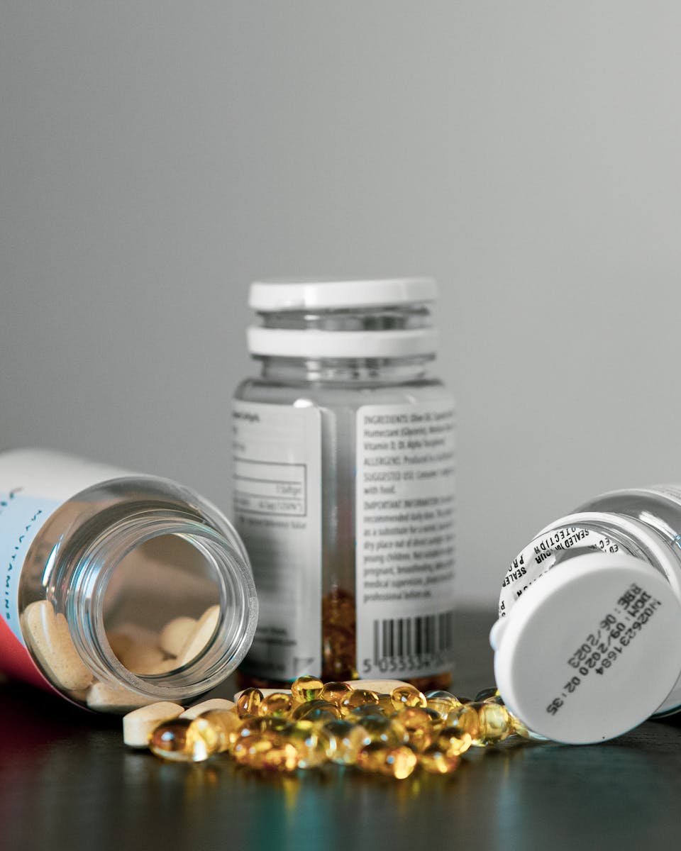 Supplement bottles with capsules and softgels spilling out, labels showing ingredient details